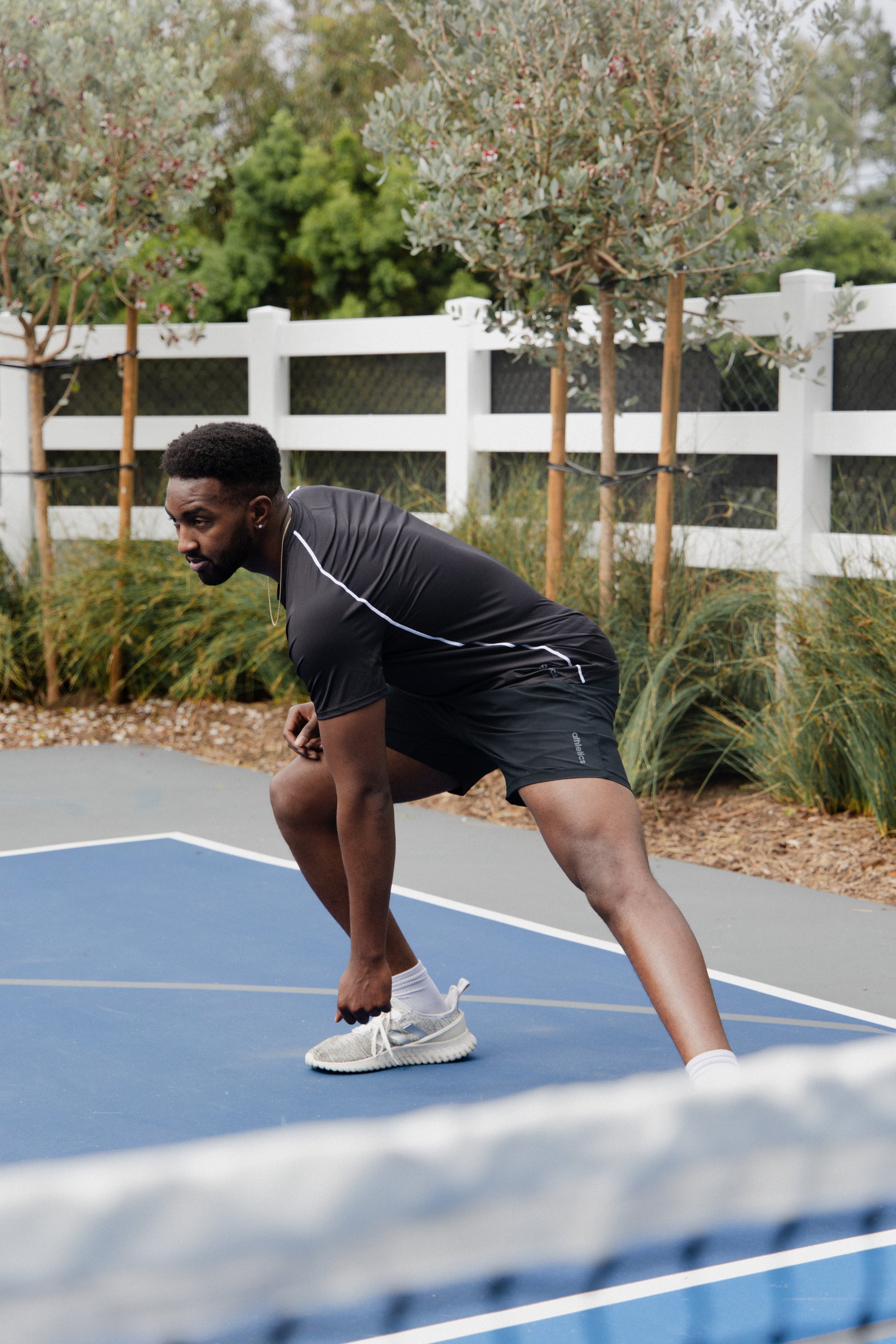 male pickleball player wearing black unlined athletic shorts and a black athletic shirt